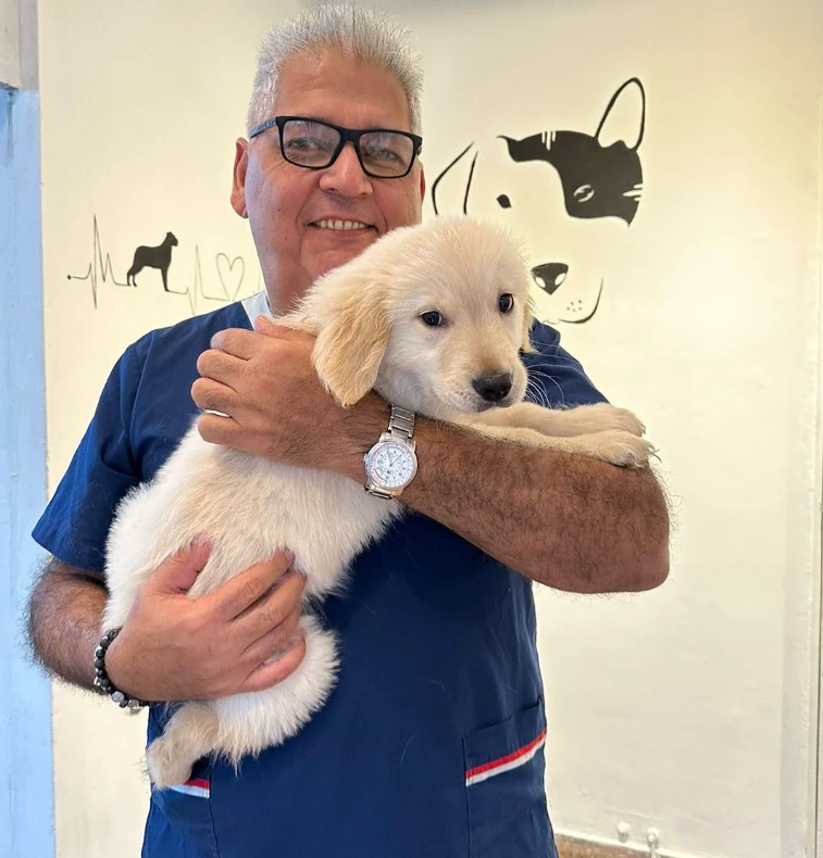 Gustavo Herrera sonriendo con un cachorro golden retriever en brazos