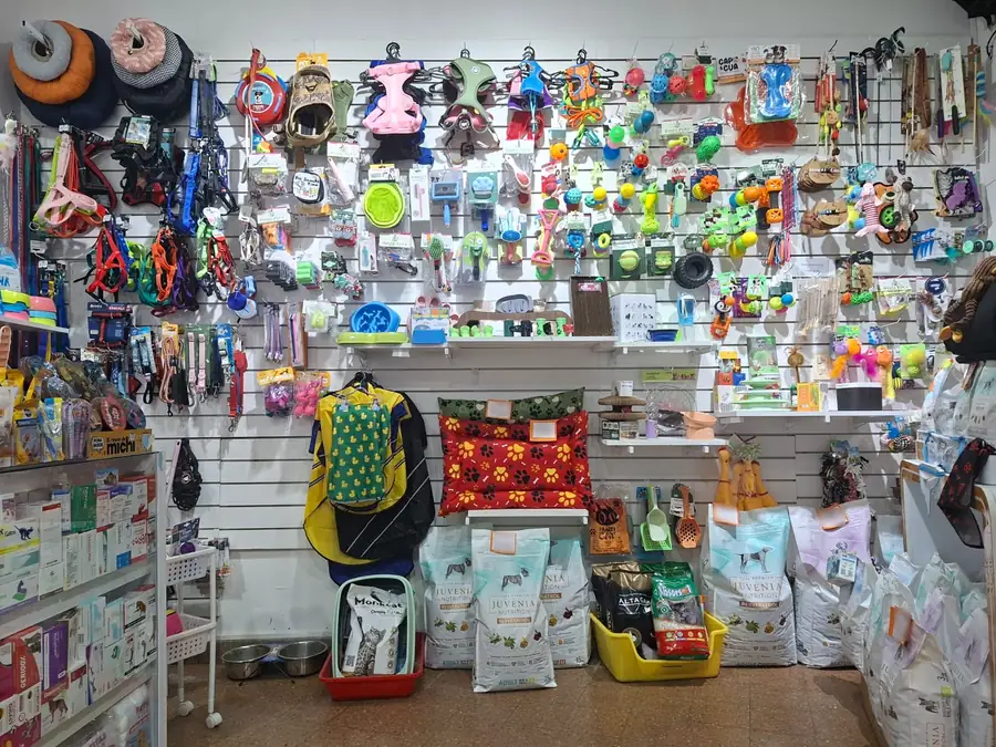Pared del pet shop llena de productos: arneses, correas, juguetes, camas y bolsas de alimento Juvenia