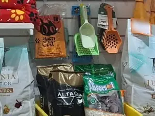 Bolsas de arena para gatos en una bandeja sanitaria y palas sanitarias colgadas en el pet shop